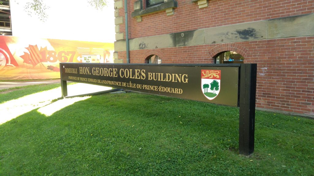 sign outside the Hon. George Coles Building with the building name and Island escutcheon (coat of arms).